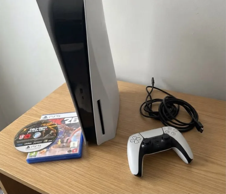 The same photo after AI editing in the styled setting mode: the console, controller, cables and games on a clear wooden desk.