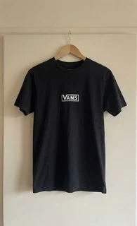 The same T-shirt on a hanger against a light wall.